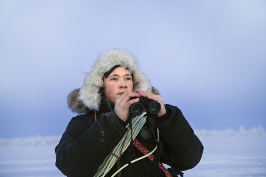 Reingjeter Bilde av en reingjeter med kikkert i hånden og lasso rundt skuldrene.