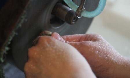 Stone Bilde av steinsliping. Hender holder stein.