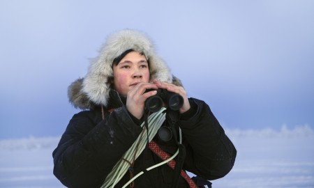 Reingjeter Bilde av en reingjeter med kikkert i hånden og lasso rundt skuldrene.