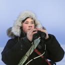 Bilde av en reingjeter med kikkert i hånden og lasso rundt skuldrene.